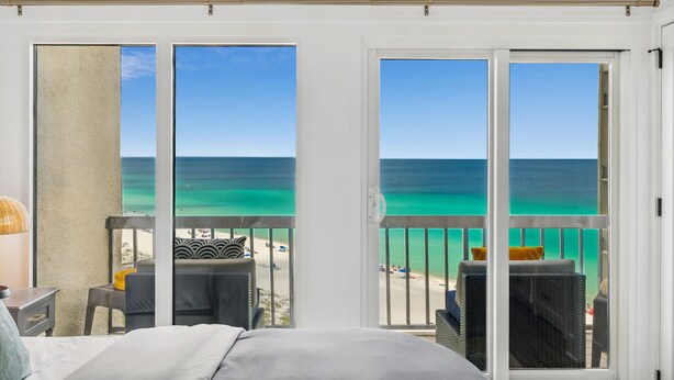 A hotel room with a balcony overlooking a beach and the ocean.