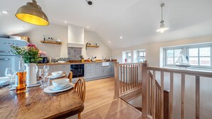 A spacious kitchen with a wooden dining table, built-in appliances, and a view to the upper floor. - Mill View Burnham Norton - sleeps 4 guests  in 2 bedrooms (Burnham Norton)