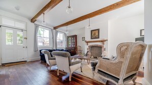 A spacious living room with hardwood floors, a fireplace, and a large window. - Edinburgh House - sleeps 8 guests  in 4 bedrooms (Burnham Market)