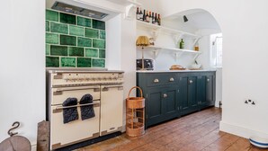 A kitchen with a vintage stove, green-tiled backsplash, wooden flooring, and dark blue cabinets. - Edinburgh House - sleeps 8 guests  in 4 bedrooms (Burnham Market)