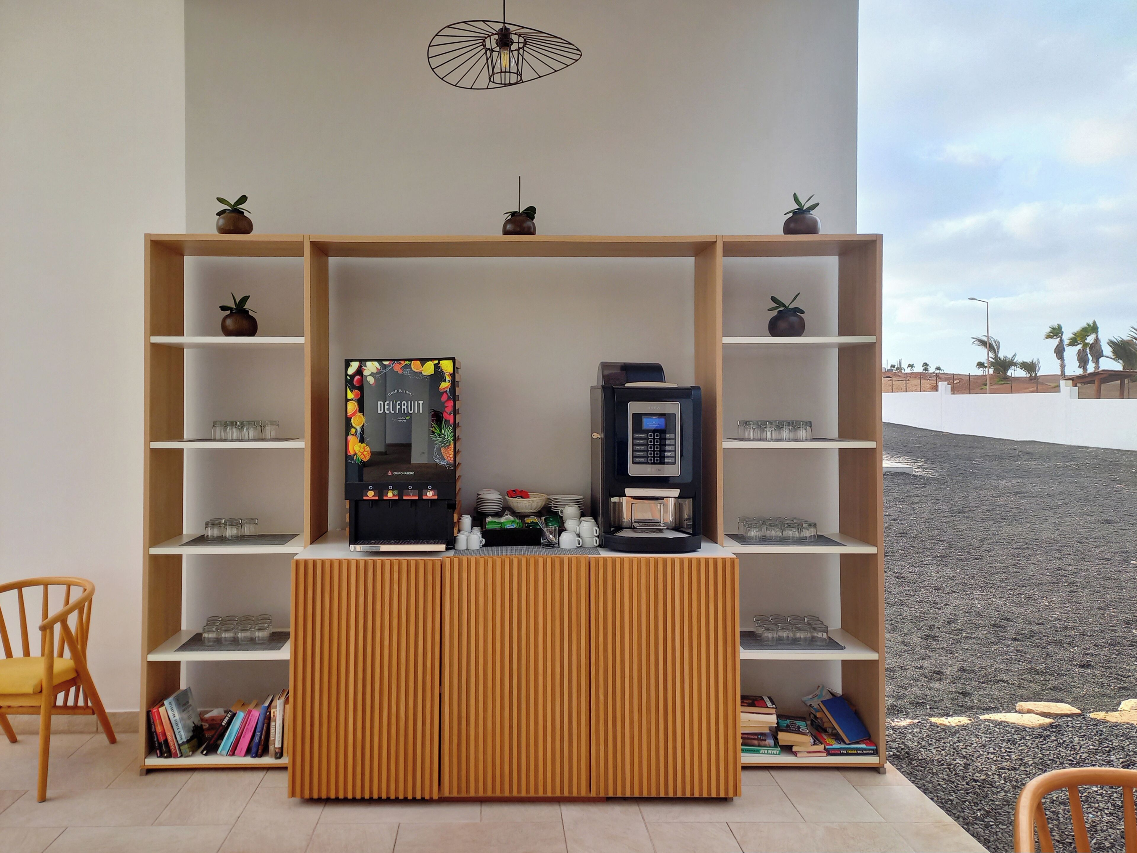 A modern room with a coffee machine, shelves with glasses, and a wooden cabinet.