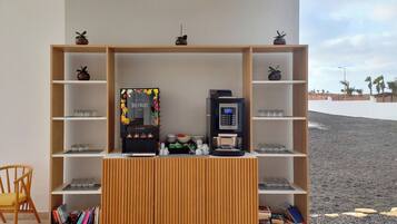 A modern room with a coffee machine, shelves with glasses, and a wooden cabinet.