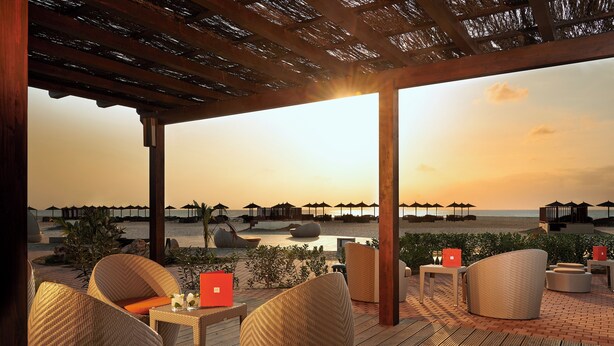 A beachside patio with wicker furniture, a laptop, and a sunset view. - Sol Dunas Family Fun (Sal)
