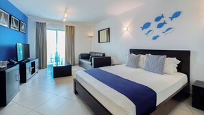 A hotel room with a large bed, a TV, a desk, and a balcony with curtains. - Sol Dunas Family Fun (Sal)