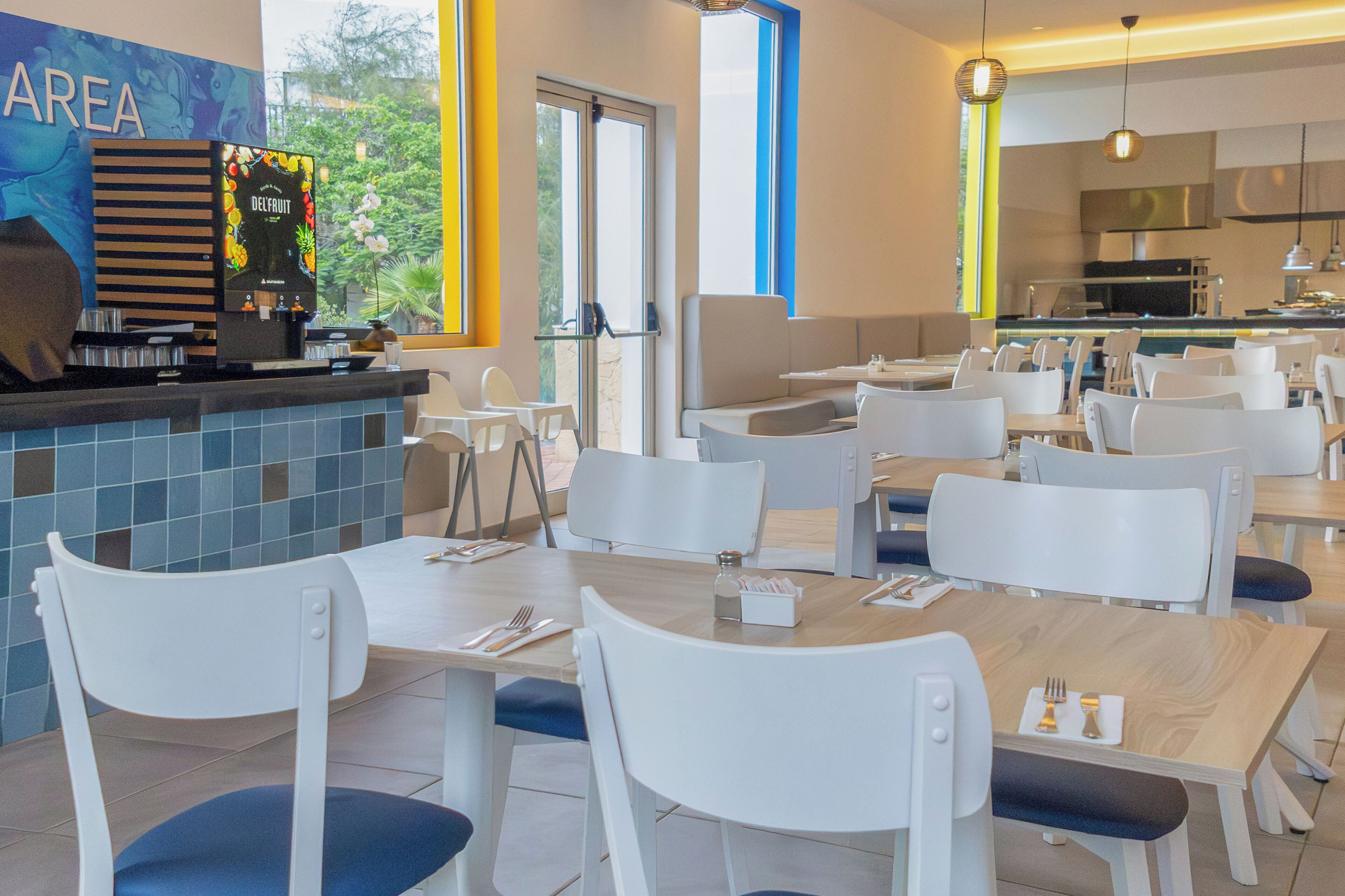 Un ristorante moderno con sedie e tavoli bianchi, una macchina per caffè e vista sull'esterno.