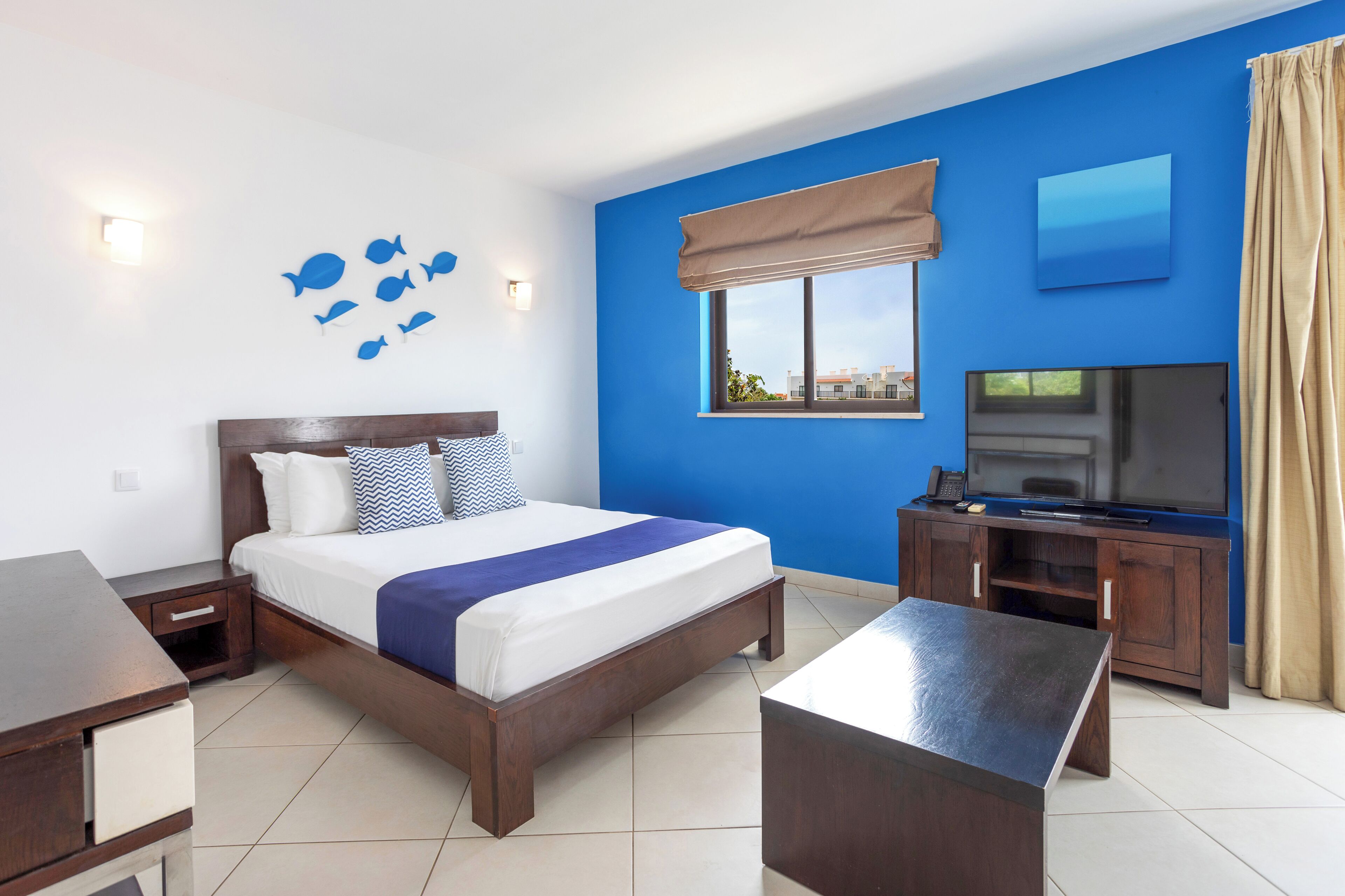 Una habitación de hotel con cama, televisión, escritorio y ventana con vistas.