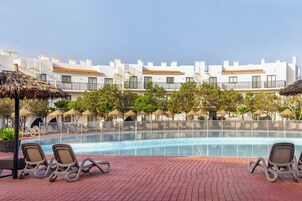 Una piscina al aire libre, sombrillas, tumbonas