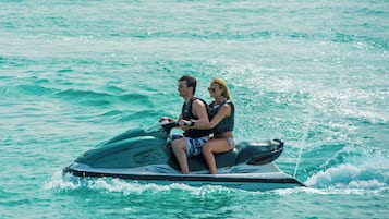 Dos personas en un jet ski sobre aguas turquesas.
