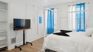 A bedroom with a bed, a TV on a stand, and a wardrobe.