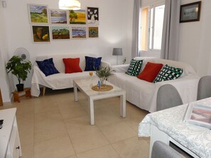 A living room with a sofa, a coffee table, a lamp, and artwork on the wall.