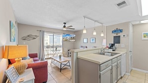 Un espacio habitable compacto con kitchenette, zona de comedor y sofá.