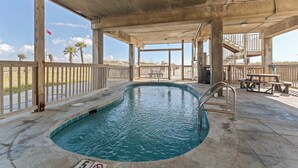Una piscina interior con suelo de hormigón, barandillas de madera y vistas a la playa.