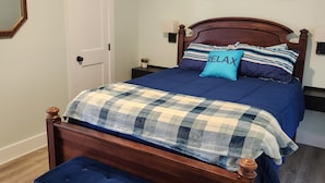 Ein Schlafzimmer mit einem Holzbett, einer blauen Bank, einem Deckenventilator, einer Tür und einem Gemälde an der Wand.
