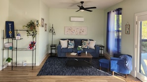 Ein Wohnzimmer mit blauem Sofa, Couchtisch, Stehlampe und Deckenventilator.