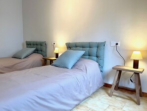 Een slaapkamer met twee bedden, elk met hoofdeinde en nachtkastjes met lampen.
