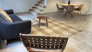 Un salon moderne comprenant un canapé, un banc, une table à manger avec des chaises et un escalier.