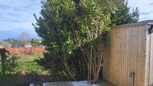 A wooden deck with a built-in planter and a small shed in the background. - Vacation home at the gateway to Ile d'Oleron (Bourcefranc-le-Chapus)