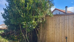 A wooden deck with a gravel border, surrounded by a wooden fence and trees. - Vacation home at the gateway to Ile d'Oleron (Bourcefranc-le-Chapus)