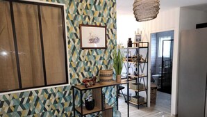 A modern kitchen with geometric patterned wallpaper, a framed picture, and open shelving with decorative items. - Vacation home at the gateway to Ile d'Oleron (Bourcefranc-le-Chapus)