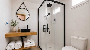 Ein modernes Badezimmer mit einer glasumrandeten Dusche, einem Holzlagerflansch mit schwarzem Waschbecken und einer Toilette.