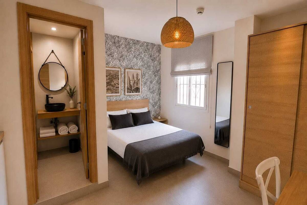 A bedroom with a bed, a bedside table, a mirror, a wardrobe, and a window.