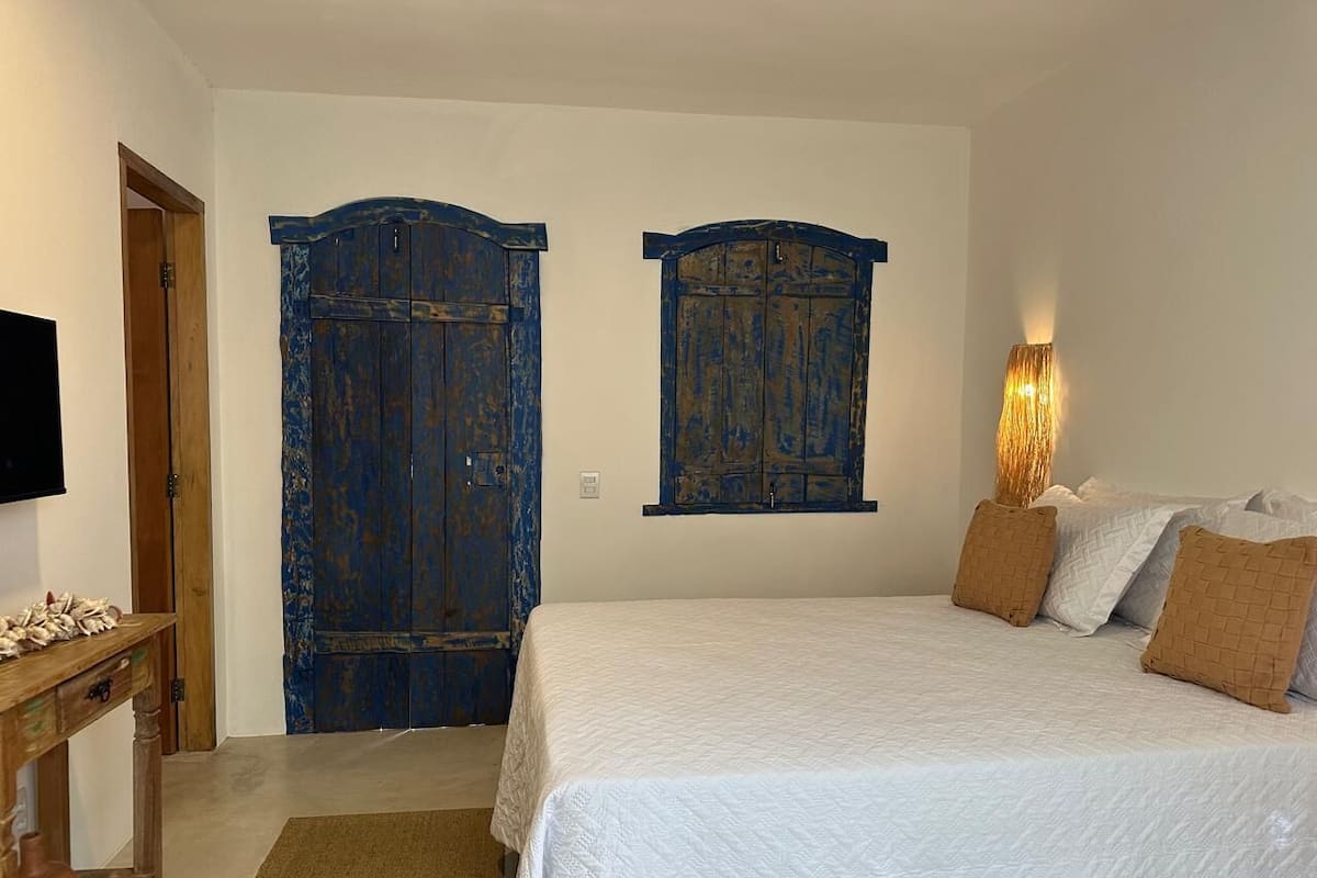 Un dormitorio con cama, mesita de noche de madera, lámpara y armario.