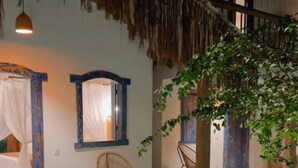 Una construcción con techo de paja, un muelle de madera, una silla y una lámpara colgante.