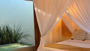 Un dormitorio con cama a dosel, una mesita y vistas al exterior.
