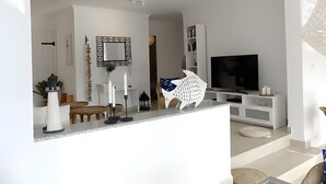Un salon moderne avec un téléviseur, des meubles blancs, une cheminée et un miroir décoratif.