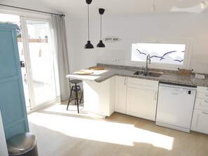 A modern kitchen with a dishwasher, a window with a decorative view, and a 'Happy Hour' sign.