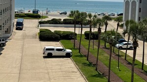 Ein Parkplatz mit mehreren Autos, ein Gebäude mit modernem Design und Blick auf Strand und Meer.