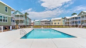A swimming pool surrounded by colorful buildings with balconies, a clear sky, and a fenced area. - NEW The Funky Oyster A4 w/Pool access Port  St Joe (Port St. Joe)