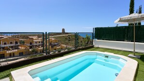 Piscina com vista para edifícios e uma cerca.