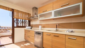 Uma cozinha moderna com armários de madeira, lava-louças de aço inoxidável e uma janela ampla com vista.
