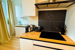 Une cuisine moderne équipée d’une plaque de cuisson à induction noire, d’une machine à café, d’une bouilloire et d’un grille-pain, le tout posé sur le plan de travail.