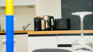 Une cuisine équipée d’une machine à café, d’une bouilloire et d’un mixeur, le tout posé sur le plan de travail.