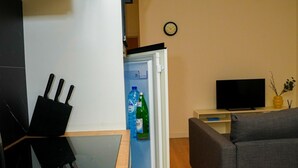 Un espace de vie compact comprenant un réfrigérateur, un téléviseur à écran plat, un canapé et une table à manger.