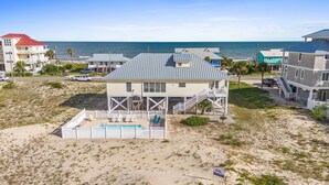 A beachfront property with a pool, a covered deck, and a view of the ocean.