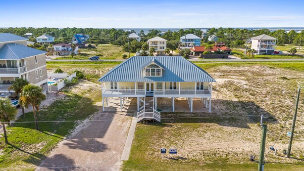 A beachfront house with a large porch, multiple levels, and a view of the ocean.