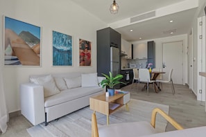 Uma sala de estar moderna com um sofá, uma mesa de centro e um espaço de jantar com cadeiras e uma mesa.
