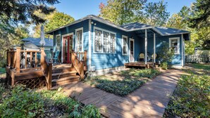 A blue house with a wooden deck, a covered porch, and a garden path.
