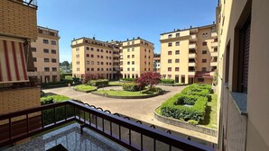 Een binnenplaats met appartementencomplexen, een centrale ronde tuin en een balkonhek.