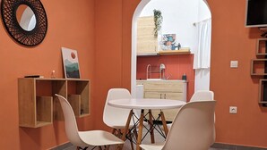 Ein stilvoller Essbereich mit einem runden Tisch, weißen Stühlen und einem gewebten Teppich.