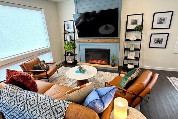 Living room area with all leather seating, fireplace, and 72" Roku TV.
