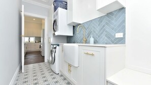 A modern kitchen with a built-in washer, a herringbone-patterned backsplash, and a gold faucet. - Stellaview Estate | Stunning View (Lower Belford)