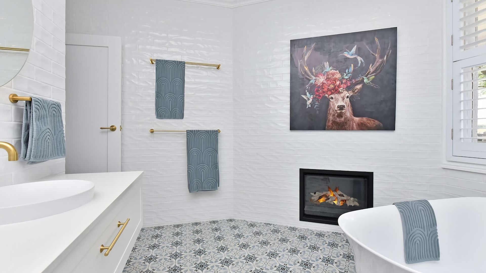 Ein Badezimmer mit weiß gefliester Wand, einer weißen Badewanne, einem weißen Waschbecken und einem Bild mit einem Hirsch und Geweihen.