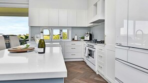A modern kitchen with white cabinetry, a central island, and a view of the outdoors. - Stellaview Estate | Stunning View (Lower Belford)