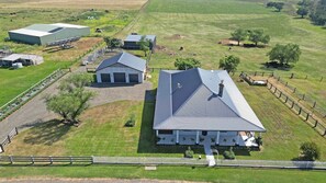 Luchtbeeld van een boerderij met een grote schuur, kleinere gebouwen en omheinde weiden.