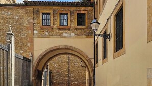 A narrow stone-paved alleyway with a stone archway, flanked by buildings with arched windows and a tiled roof. - AH La Crème de la Crème. Oviedo. ENT200112814125 (Oviedo)