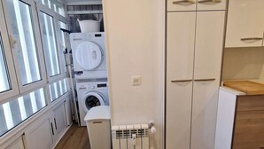 Une cuisine compacte dotée d’appareils électroménagers intégrés, d’un radiateur et d’un plancher en bois.